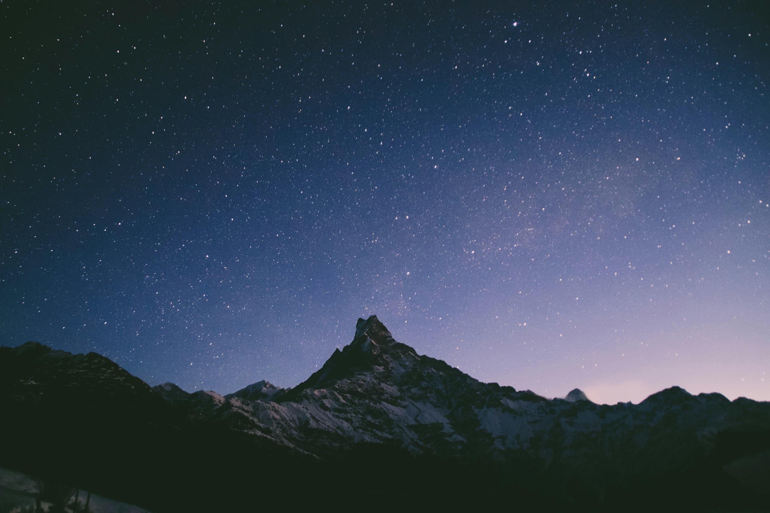 A starry night sky over a mountain peak